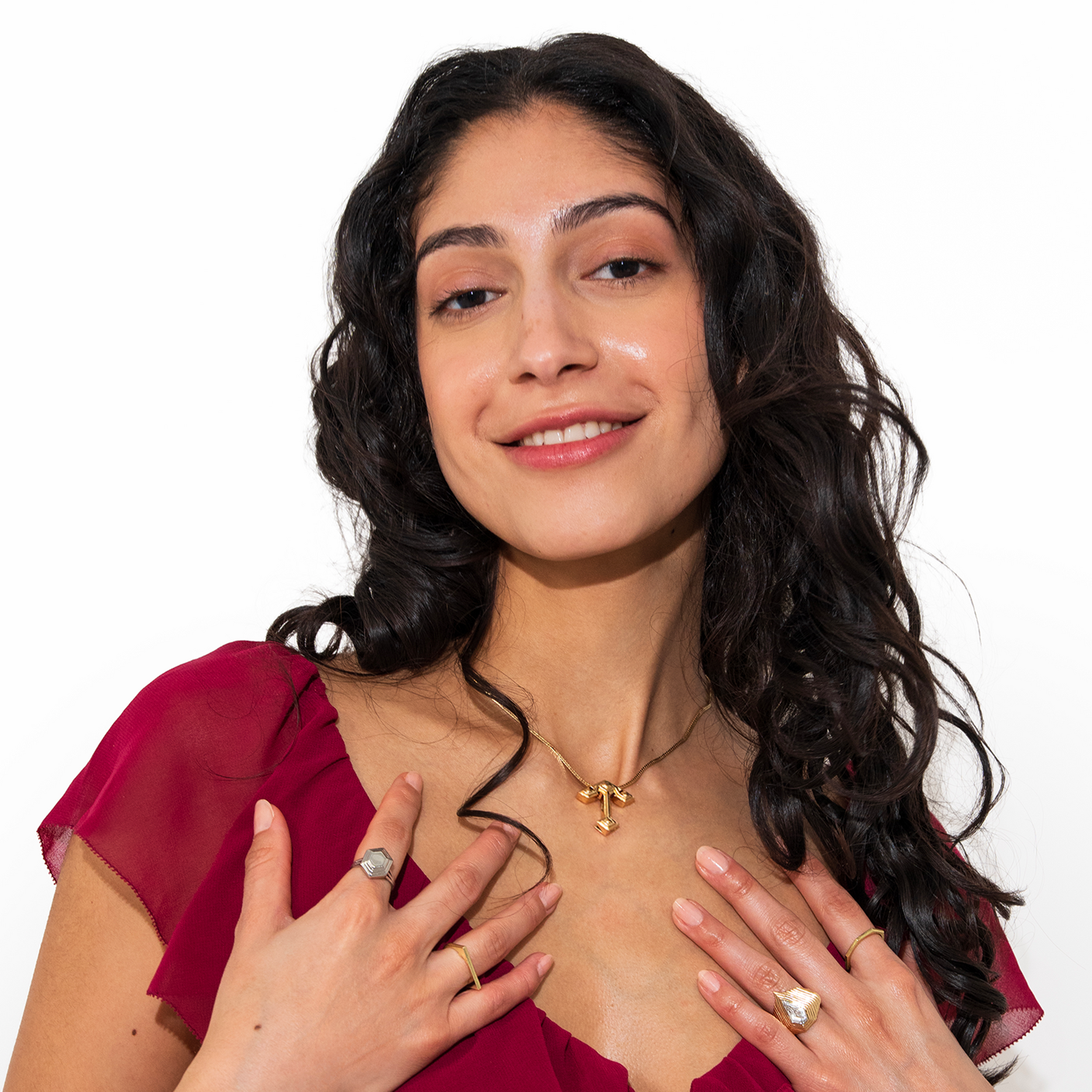 Woman wearing Root Anchor Pendant framed in v neck red burgundy dress and curly hair with rings